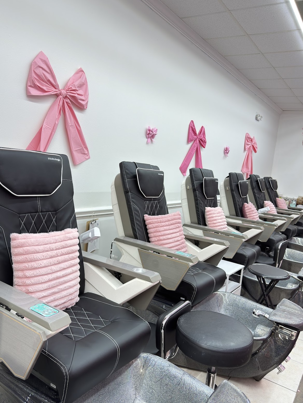 The cozy pedicure area at ES Nail Spa, with black spa chairs and pink bow accents